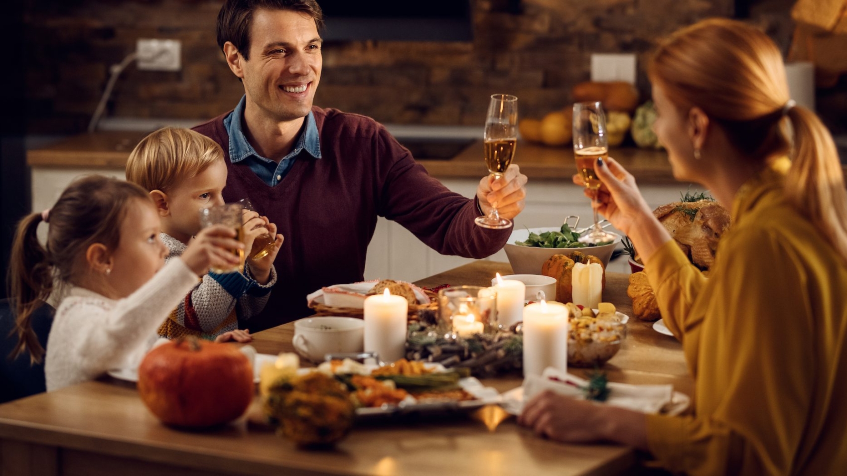 Happy family toasting while having Thanksgiving dinner at dining table. Focus is on father.