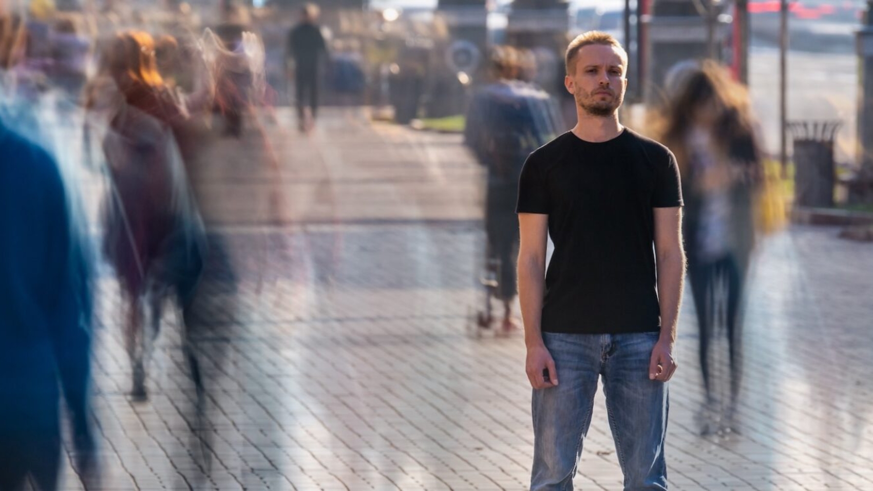 The young man stands in the middle of crowded street