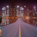 Backpacker standing on the road in the city and looking to the skyscrapers.